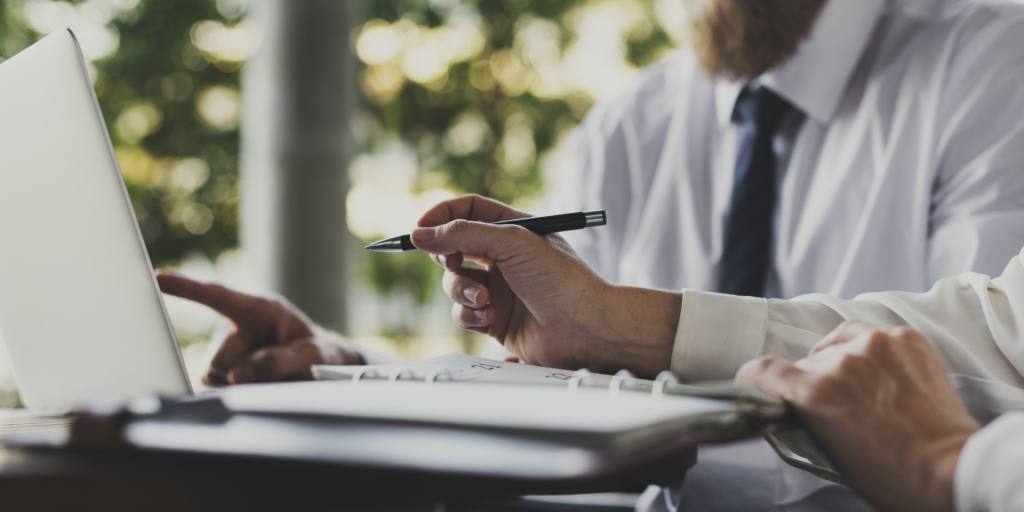 Zwei Personen in Businesskleidung arbeiten an einem Laptop und überprüfen Unterlagen, symbolisierend die Planung und Eigenständigkeit beim provisionsfreien Immobilienverkauf.