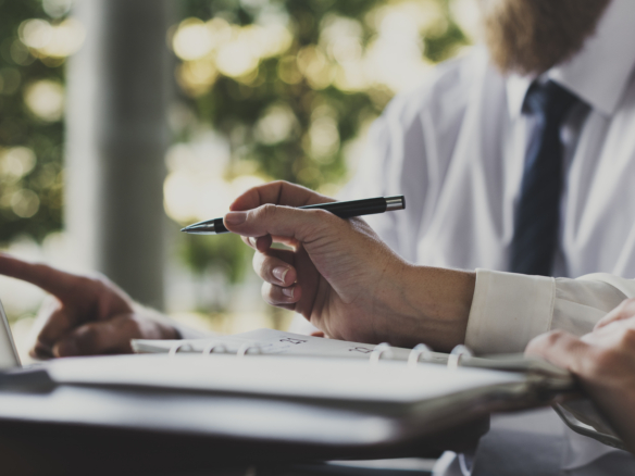 Zwei Personen in Businesskleidung arbeiten an einem Laptop und überprüfen Unterlagen, symbolisierend die Planung und Eigenständigkeit beim provisionsfreien Immobilienverkauf.