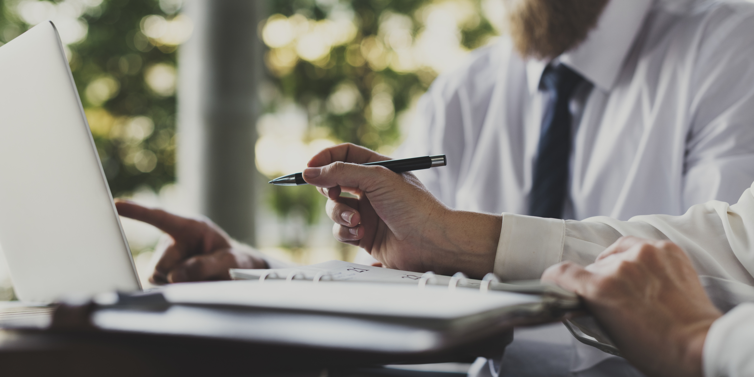 Zwei Personen in Businesskleidung arbeiten an einem Laptop und überprüfen Unterlagen, symbolisierend die Planung und Eigenständigkeit beim provisionsfreien Immobilienverkauf.